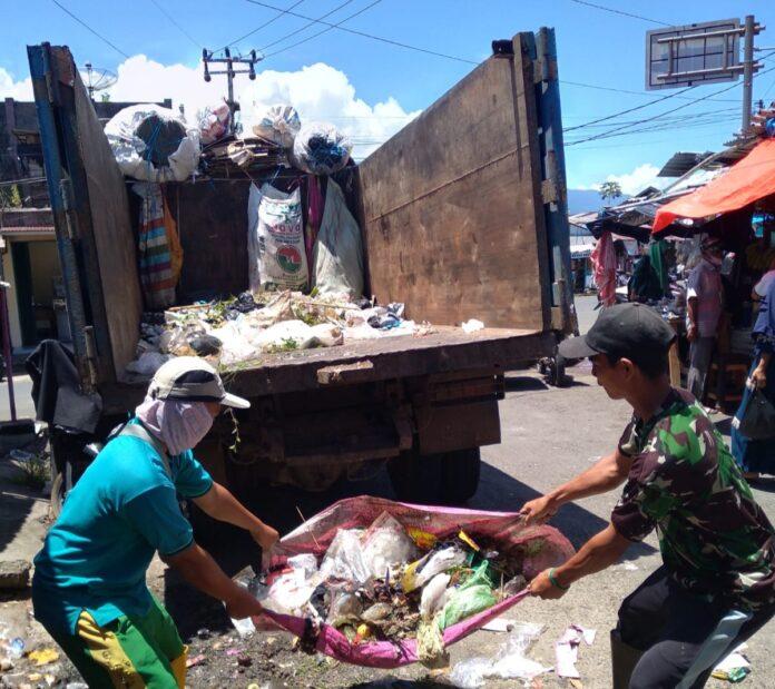 Momen petugas menaikkan sampah ke dalam mobil pengangkut.